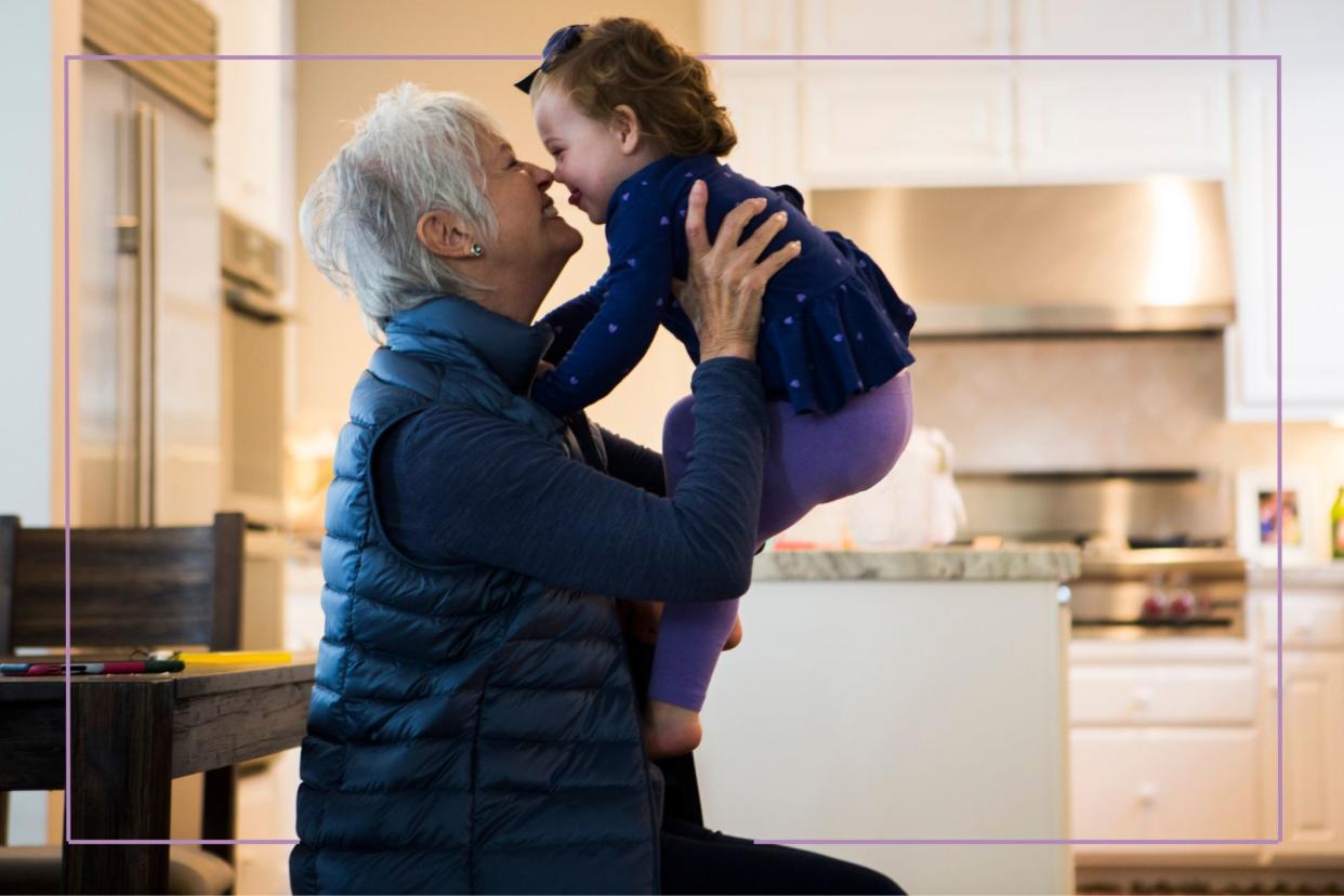  Older lady with cropped silver hair lifting a toddler above her head. 