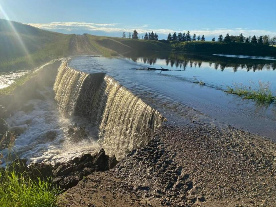 Water rushes over a damaged Township Road 210 in the Rural Municipality of Edenwold. (Submitted by Rural Municipality of Edenwold - image credit)