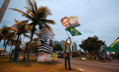 A supporter of Brazilian presidential candidate Jair Bolsonaro is seen next to an inflatable doll, also known as Pixuleco, depicting former Brazilian president Luiz Inacio Lula da Silva, in front of Bolsonaro's condominium at Barra da Tijuca neighborhood in Rio de Janeiro, Brazil October 5, 2018. REUTERS/Sergio Moraes