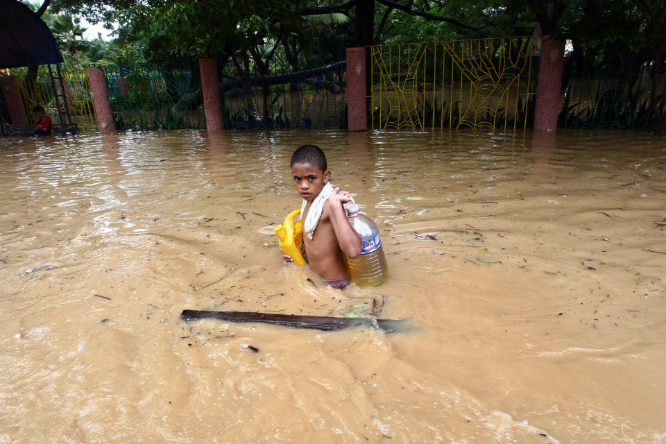 A boy carries supplies through waist-high floodwater in Pasig City in Manila, the capital. On Sept. 30,&nbsp;2009, in the Philippines, over half a million people are displaced by flooding caused by Tropical Storm Ketsana, which struck on Sept. 26. The storm dumped over a month's worth of rain on the island of Luzon in only 12 hours. The flooding has affected some 1.8 million people, and the death toll has climbed to 246.