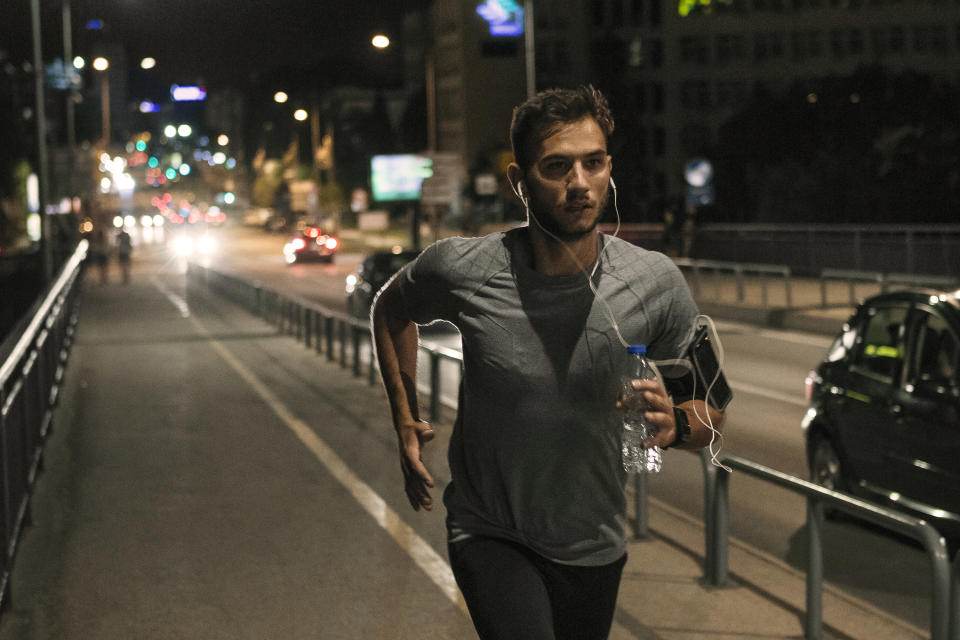 A man runs across a bridge at night