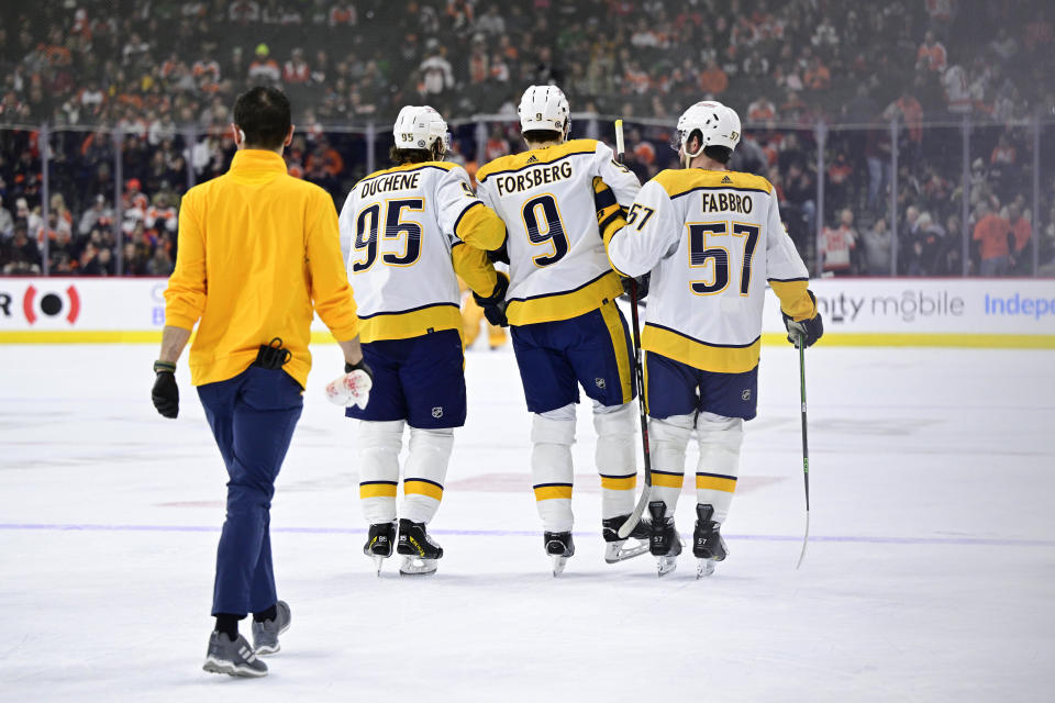 Nashville Predators' Filip Forsberg (9) is helped off the ice by teammates Matt Duchene (95) and Dante Fabbro (57) after an injury during the first period an NHL hockey game against the Philadelphia Flyers, Saturday, Feb. 11, 2023, in Philadelphia. (AP Photo/Derik Hamilton)