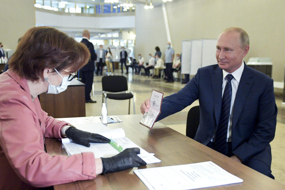 FILE - Russian President Vladimir Putin shows his passport to a member of an election commission as he arrives to take part in voting at a polling station in Moscow, Russia, on July 1, 2020. A referendum approves constitutional changes proposed by Putin, which allow him to run for two more terms starting in 2024. (Alexei Druzhinin, Sputnik, Kremlin Pool Photo via AP, File)