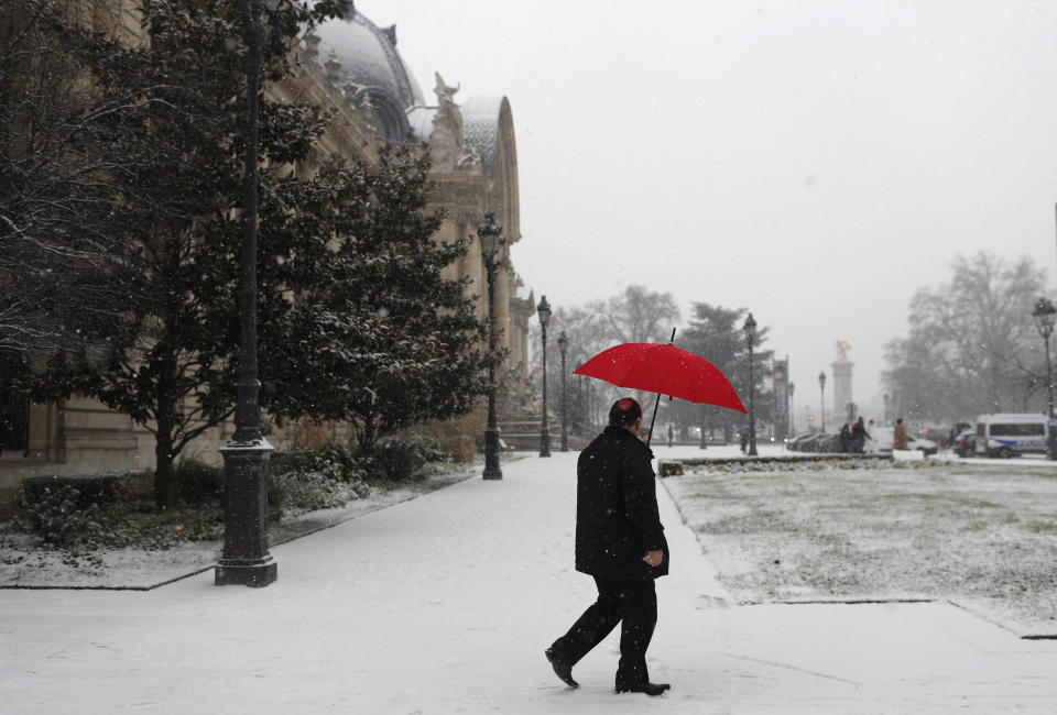 A man walks past the Grand Palais monument during snowfall in Paris, Tuesday Jan.22, 2019. (AP Photo/Thibault Camus)