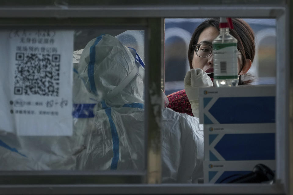 A woman gets her routine COVID-19 throat swab at a coronavirus testing site setup along a pedestrian walkway in Beijing, Thursday, Nov. 3, 2022. The ruling Communist Party is enforcing a "Zero COVID" policy that has closed areas throughout China for weeks to try to isolate every case. (AP Photo/Andy Wong)