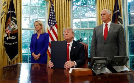 U.S. President Donald Trump sits in front of the news media after signing an executive order on immigration policy with DHS Secretary Kirstjen Nielsen and Vice President Mike Pence at his sides in the Oval Office at the White House in Washington, U.S., June 20, 2018. REUTERS/Leah Millis