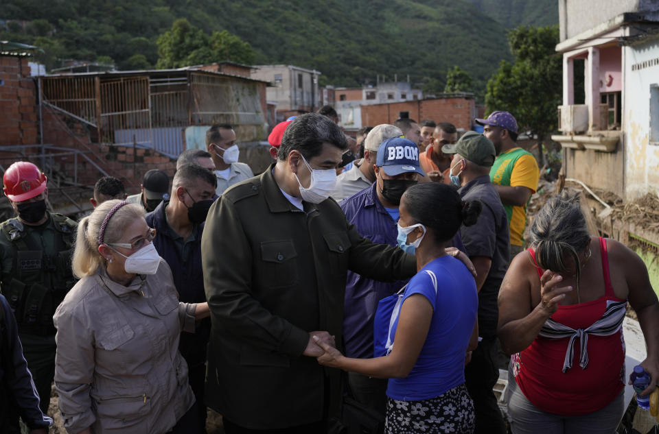 Venezuela's President Nicolas Maduro, center, and First Lady Cilia Flores, left, talks to the victims as the visit the area damaged during the flood in Las Tejerias, Venezuela, Monday, Oct. 10, 2022. A fatal landslide fueled by flooding and days of torrential rain swept through this town in central Venezuela. (AP Photo/Matias Delacroix)
