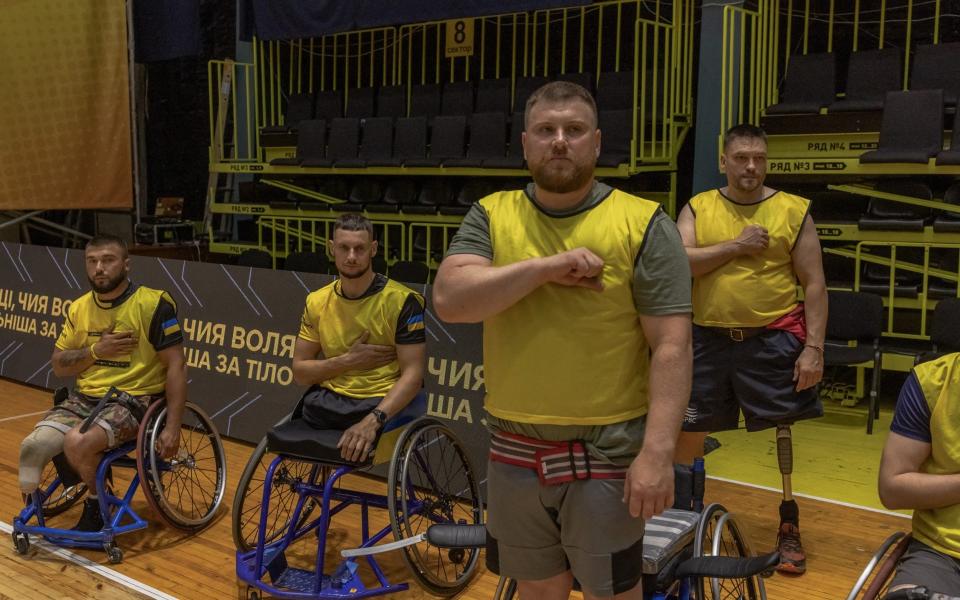 Ukrainian veterans in wheelchairs sing the national anthem before the qualifying competition to join the Ukrainian national basketball team for the Invictus Games