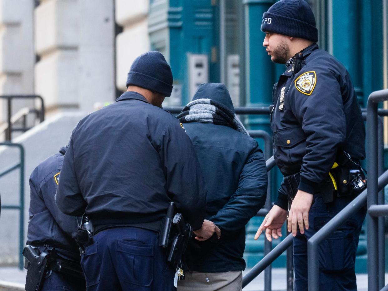Police arresting a suspect outside of her NYC apartment