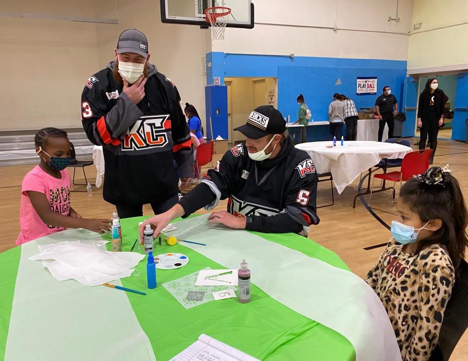 Kansas City Mavericks players Shawn Weller, left, and Willie Corrin visited the Independence Boys & Girls Club Wednesday and joined Kennyeyae Butler, left, and Anabel Borja as they painted a table runner that will be used and auctioned at the upcoming Dinner on Ice, a charity event that benefits the area Boys & Girls Clubs.