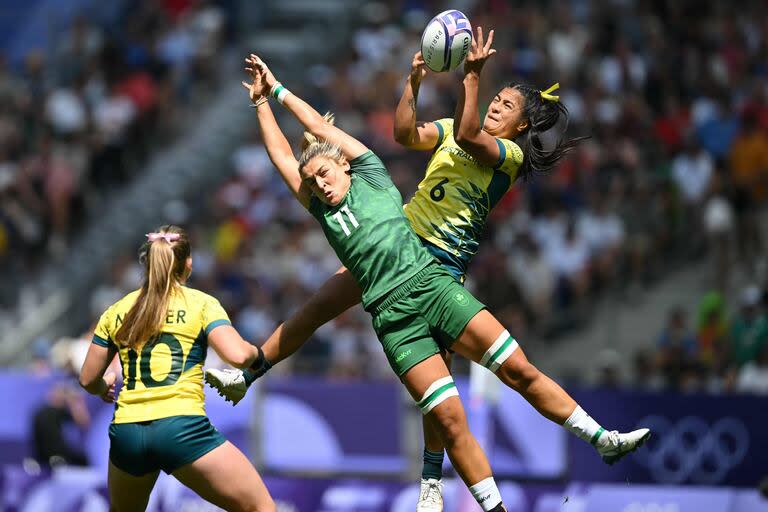 La australiana Sariah Paki (derecha) atrapa la pelota desafiada por la irlandesa Erin King (centro) durante el partido de rugby sevens femenino del grupo B entre Australia e Irlanda durante los Juegos Olímpicos de París 2024 en el Stade de France en Saint-Denis el 29 de julio de 2024. (Foto de CARL DE SOUZA / AFP)