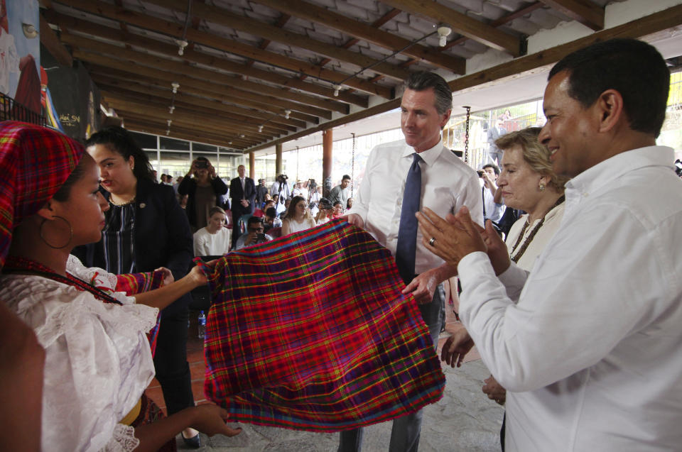 California Gov. Gavin Newsom receives a traditional Panchimalco hand-made textile during his visit in Panchimalco, El Salvador, Monday, April 8, 2019. At right, Panchimalco Mayor, Mario Melendez. (AP Photo/Salvador Melendez)