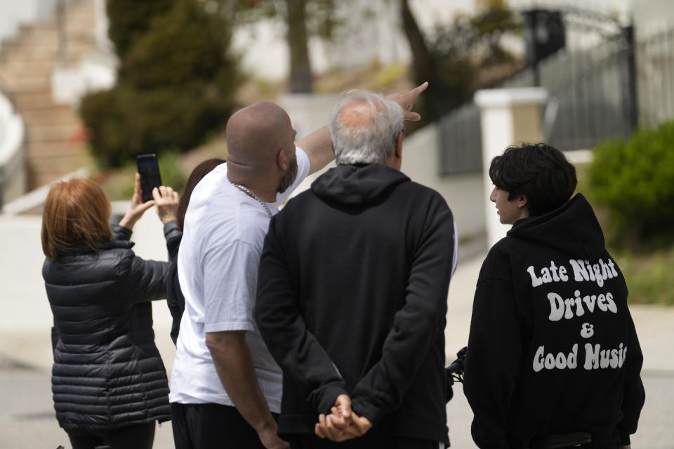 Resident Joubin Solemani, second from left, with his family look up as Los Angeles City Fire Department's Urban Search and Rescue members assist in recovering the pilot's body of a downed Cessna C172 on a steep hill above a home on Beverly Glen Circle in Los Angeles, Sunday, April 30, 2023. Fire department officials said a person was found dead following an intensive search for the single-engine airplane that crashed in a foggy area Saturday night. (AP Photo/Damian Dovarganes)