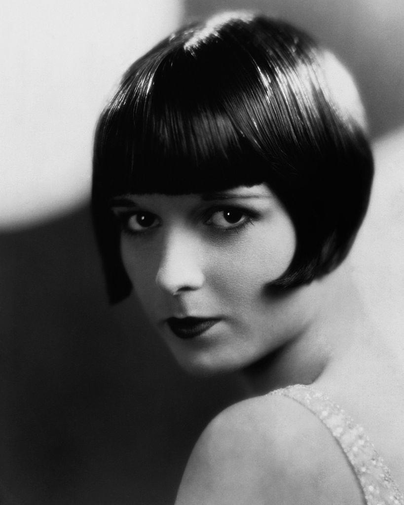 Louise Brooks with a sleek bob haircut and flapper style makeup, looking over her shoulder