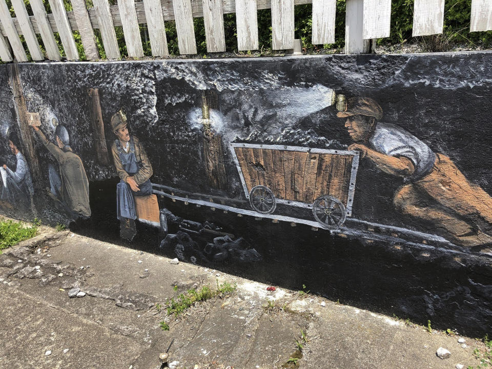 In this Tuesday, May 12, 2020, photo is a mural depicting miners working in coal mines in Matewan, W.Va. On May 19, 1920, a group of miners, who were led by a local police chief, and detectives hired by a coal company to evict unionizing miners from their homes were involved in a gun battle on the street. Ten people died in the Matewan Massacre. (AP Photo/John Raby)