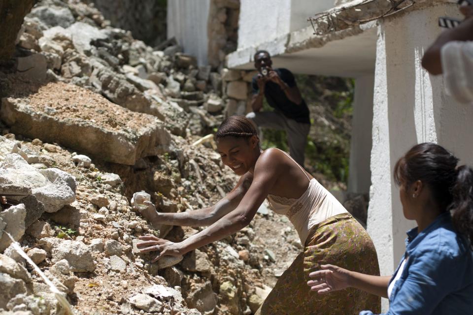 Nigerian-German singer-songwriter Ayo, center, makes her way around rubble during the filming of "Murder in Pacot" at a home that was damaged in real life by the 2010 earthquake in Port-au-Prince, Haiti, Friday, April 11, 2014. Haiti's most respected filmmaker, Raoul Peck, began production on a new film in Haiti this week, making perhaps the first feature to dramatize how people faced the days and weeks after the 2010 earthquake. (AP Photo/Dieu Nalio Chery)