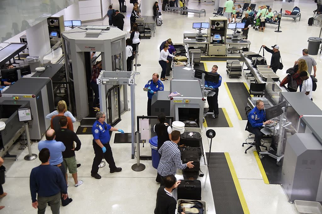 Transportation Security Administration (TSA) officers inspect airline passengers before they board their flights (AFP via Getty Images)