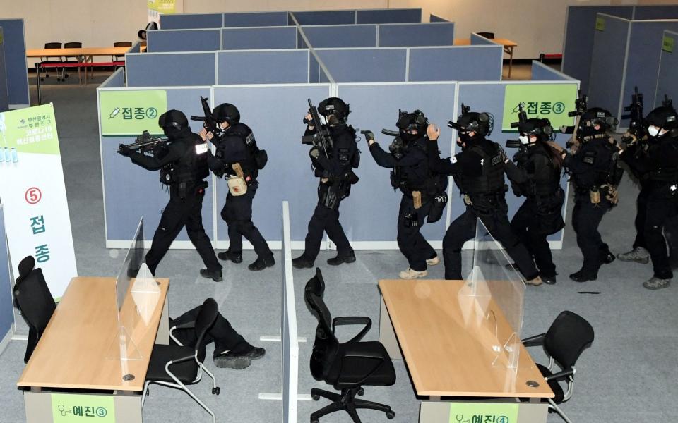 Members of the police special forces enter a Covid-19 vaccination center during a drill in the southeastern port city of Busan, South Korea. Anti-terror drill was conducted based on a scenario of a terrorist group abducting medical staff and stealing vaccines against the new coronavirus following its commandeering of the center - YONHAP/EPA-EFE/Shutterstock 