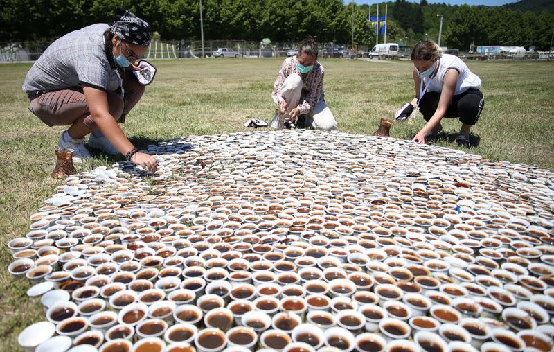 Artist Aida Sehovic helps sets up the installation of some 8,000 traditional ceramic cups filled with Bosnian coffee at the Potocari-Srebrenica Memorial Centre for victims of the 1995 massacre of Muslim men and boys by Serb forces