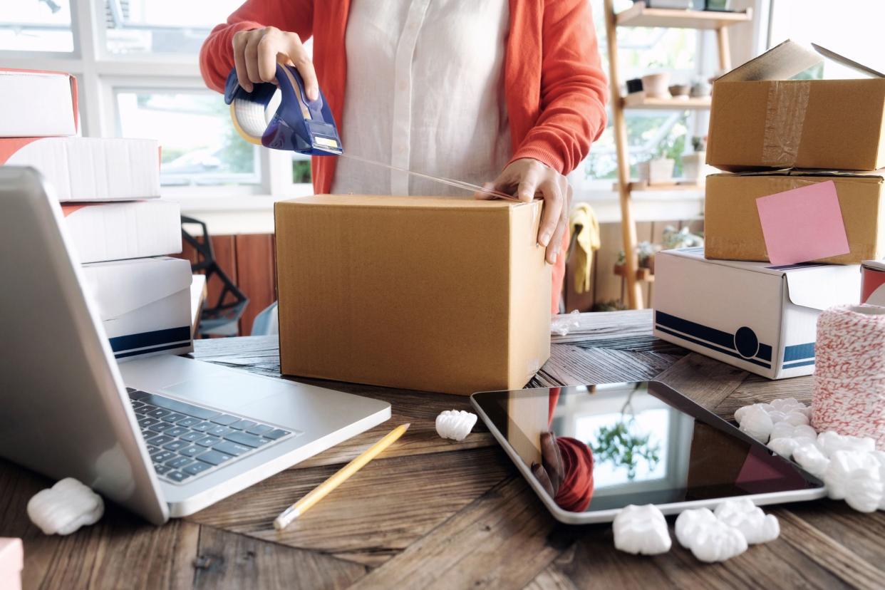 Woman packing boxes next to open laptop