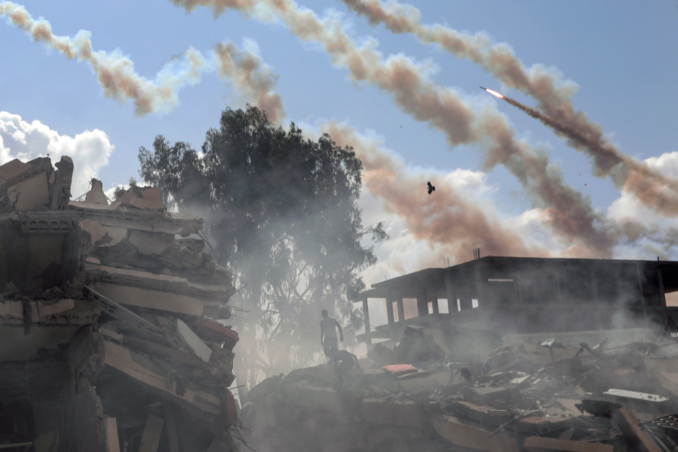 Qassam rockets fly over destroyed buildings following Israeli airstrikes on Gaza City (AP)