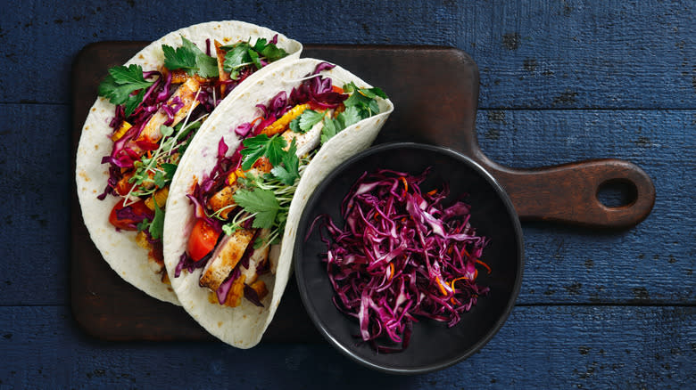 Chicken tacos in flour tortillas on board with slaw