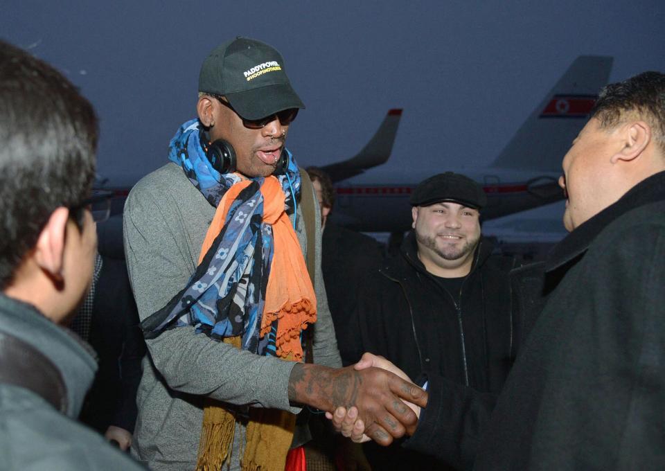 Retired U.S. basketball star Dennis Rodman shakes hands with officials upon arrival at Pyongyang airport