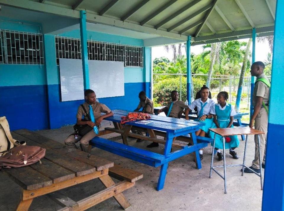 Students are seated outdoors beneath a gazebo that serves as both a classroom and a place for them to have lunch due to overcrowding at McGrath High School in Treadways, Jamaica. Friday's Rafe Cochran Golf Classic will fund construction of two buildings with six classrooms at the school.