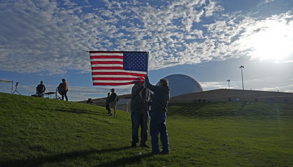 As solar eclipse festivities heat up Monday morning, Mike Bostwick (left) of Swartz Creek, MI and Tony Achilles of Downers Grove, IL, plant an American flag at the Neil Armstrong Air u0026 Space Museum in Wapakoneta, Ohio.