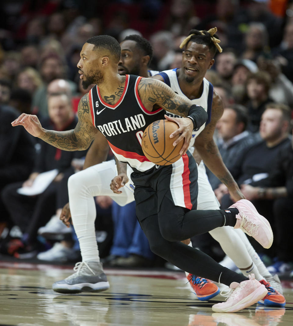 Portland Trail Blazers guard Damian Lillard, left, dribbles past Dallas Mavericks forward Reggie Bullock during the first half of an NBA basketball game in Portland, Ore., Sunday, Jan. 15, 2023. (AP Photo/Craig Mitchelldyer)