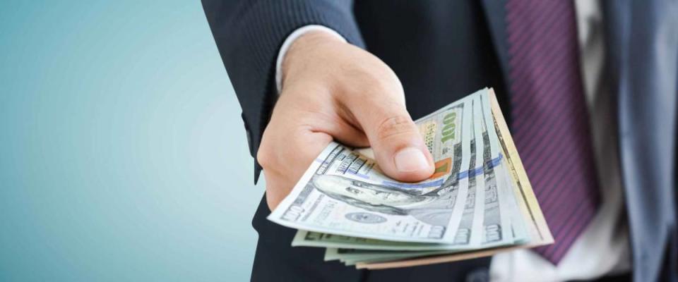 Man in suit close up of handing person pile of cash