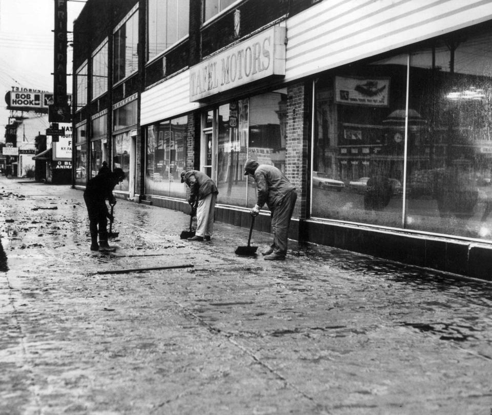 Snow shovels were used to push away the bulk of the silt left behind on East Broadway in Louisville after flood waters receded, March 10, 1964.