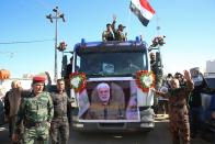 Mourners gather during a funeral procession for Abu Mahdi al-Muhandis, in the poster, deputy commander of Iran-backed militias in Basra, Iraq, Tuesday, Jan. 7, 2020. Thousands of people gathered in Basra on Tuesday to bid farewell to Abu Mahdi al-Muhandis, a senior Iraqi militia commander who was killed in a US airstrike on Friday. (AP Photo)