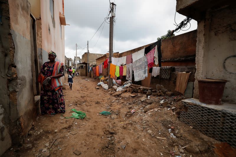 A woman stands near a wall damaged by the flood after heavy rains in Cayor on the outskirts of Dakar