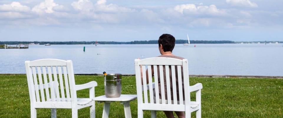 Senior lady in patio chairs drinking champagne by Chesapeake bay