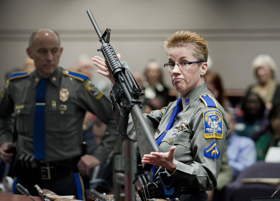 FILE - In this Jan. 28, 2013, file photo, firearms training unit Detective Barbara J. Mattson, of the Connecticut State Police, holds up a Bushmaster AR-15 rifle, the same make and model of gun used by Adam Lanza in the Sandy Hook School shooting, for a demonstration during a hearing of a legislative subcommittee reviewing gun laws, at the Legislative Office Building in Hartford, Conn. The Supreme Court said Tuesday, Nov. 12, 2019, a survivor and relatives of victims of the Sandy Hook Elementary School shooting can pursue their lawsuit against the maker of the rifle used to kill 26 people. (AP Photo/Jessica Hill, File)