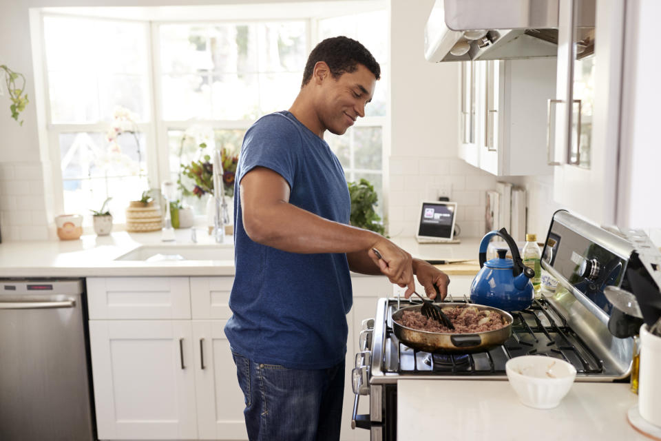 A smiling man cooking a meal on the stove