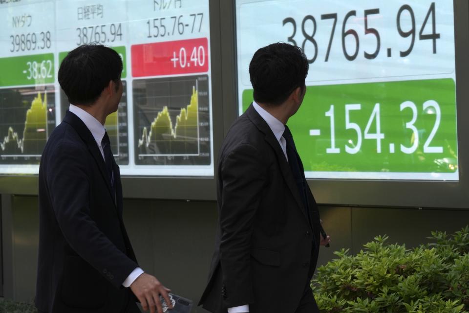 Passersby look at an electronic stock board showing Japan's Nikkei 225 index at a securities firm Friday, May 17, 2024, in Tokyo. (AP Photo/Eugene Hoshiko)