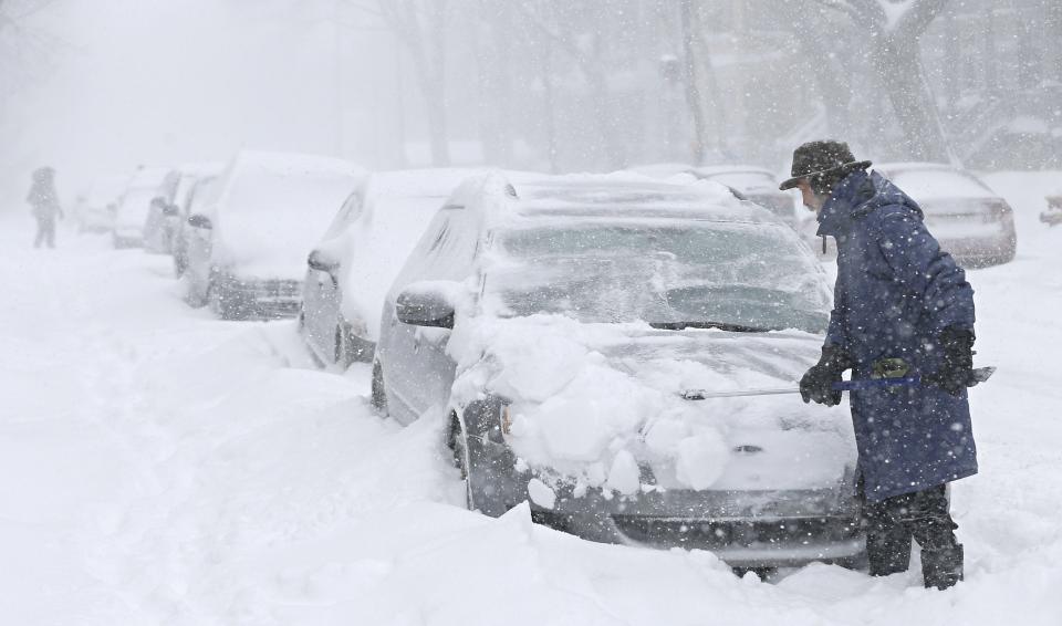 A man clears snow from his car during a snowstorm in Quebec City