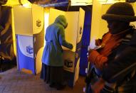 A voters stands in a voting booth to mark her ballot as another walks past in Bekkersdal, near Johannesburg May 7, 2014. (REUTERS/Mike Hutchings)