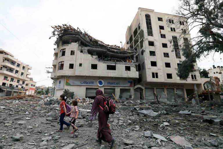 Palestinos caminan entre los escombros en medio de la destrucción masiva de los ataques aéreos israelíes en el distrito de al-Rimal de la Ciudad de Gaza.