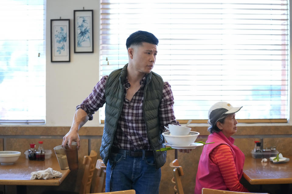 Denny Mu, owner of Mandarin Noodle House, clears a table inside his restaurant, which is about half a mile from the Star Ballroom Dance Studio, on Tuesday, Jan. 24, 2023, in Monterey Park, Calif. A gunman killed multiple people at the ballroom dance studio late Saturday amid Lunar New Years celebrations in the predominantly Asian American community. (AP Photo/Ashley Landis)