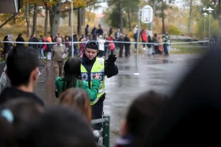 A police officer speaks to onlookers standing outside a cordoned area after a masked man attacked people with a sword at a school in Trollhattan, western Sweden October 22, 2015. REUTERS/Bjorn Larsson Rosvall/TT News Agency