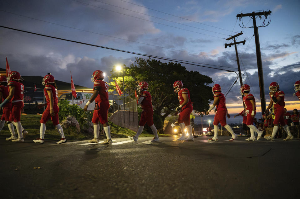 The Lahainaluna High School football team walks to the field at Sue D. Cooley Stadium, Saturday, Oct. 21, 2023, in Lahaina, Hawaii. Lahainaluna’s varsity and junior varsity football teams are getting back to normal since the devastating wildfire in August. (AP Photo/Mengshin Lin)