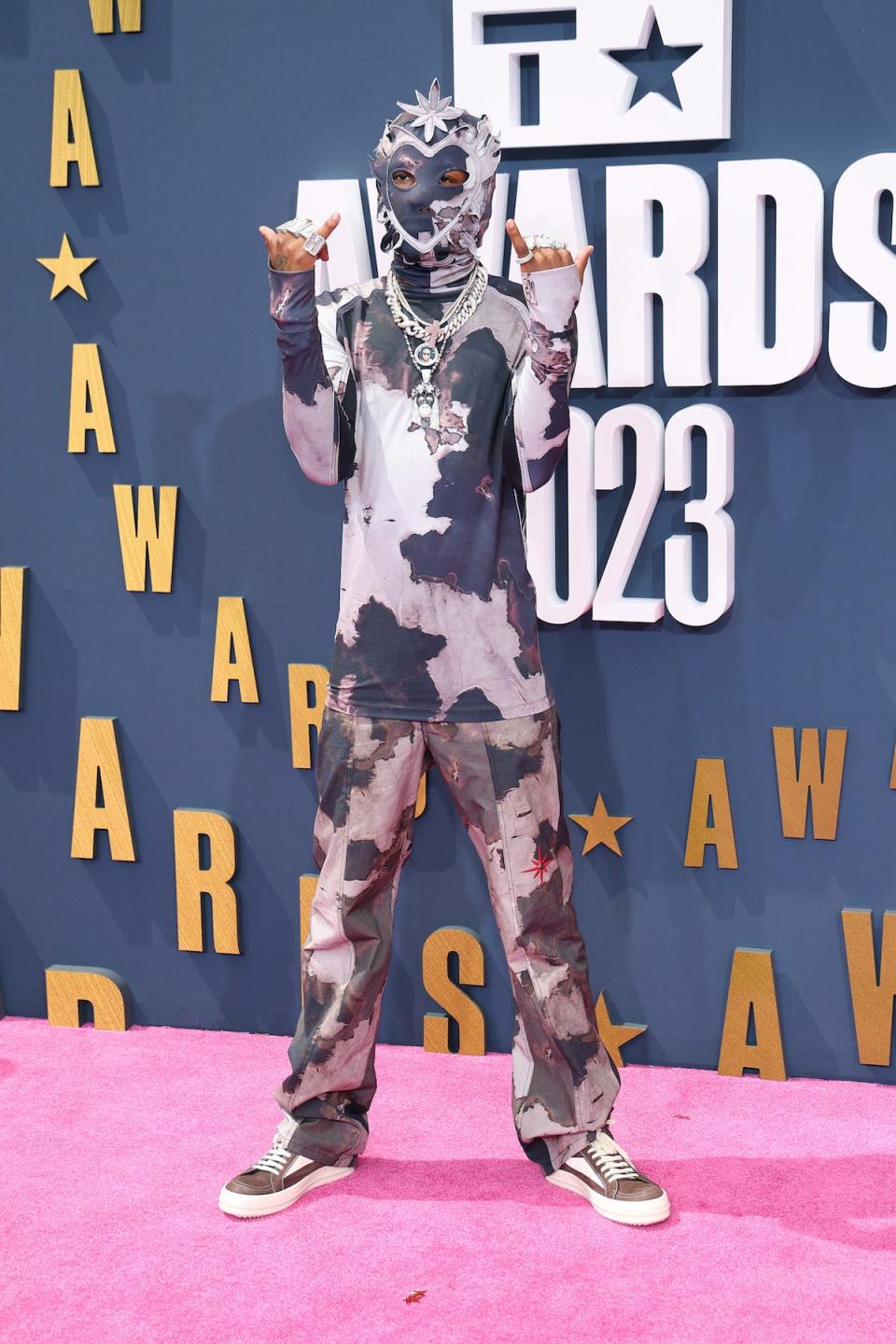 Rapper Rich the Kid poses on the red carpet at the 2023 BET Awards wearing camo-style pants and a matching shirt and balaclava.