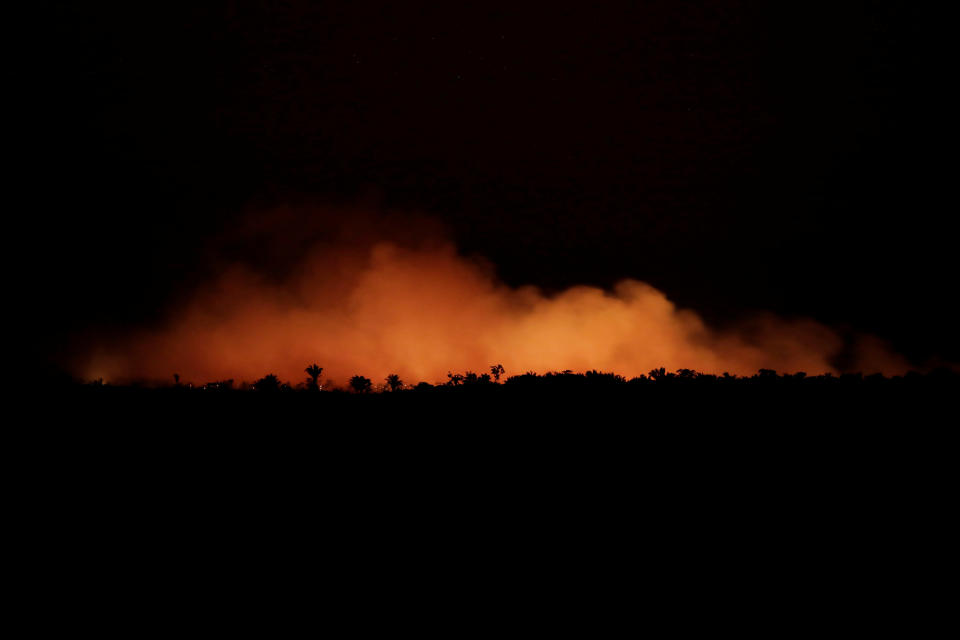 Orange smoke is seen at night during a fire in an area of the Amazon forest. Source: Reuters