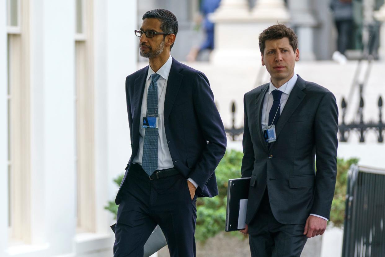Two men in suits with ID badges walk together; the taller man on the left is Sundar Pichai of Alphabet and the shorter one on the right, carrying a laptop. is investor and OpenAI guy Sam Altman