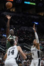 Milwaukee Bucks' Jrue Holiday, top left, shoots over San Antonio Spurs' Drew Eubanks (14) and Dejounte Murray (5) during the second half of an NBA basketball in San Antonio, Texas, Saturday, Oct. 23, 2021. (AP Photo/Chuck Burton)