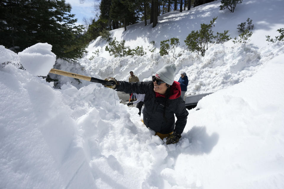 Monica Tapia, a volunteer with the disaster response group Team Rubicon, digs a resident's vehicle out of the snow, Wednesday, March 8, 2023, in Lake Arrowhead, Calif. (AP Photo/Marcio Jose Sanchez)