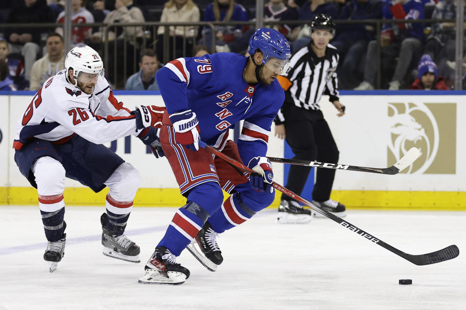 New York Rangers defenseman K'Andre Miller controls the puck past Washington Capitals right wing Nic Dowd (26) during the second period of an NHL hockey game Wednesday, Dec. 27, 2023, in New York. (AP Photo/Adam Hunger)